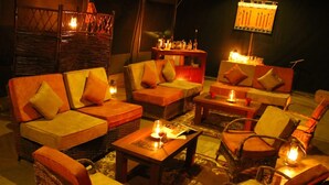 A cozy lounge area with wicker furniture, cushioned seating, and ambient lighting.