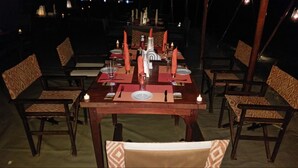 A dining table set for six with red napkins, candles, and a central decorative piece.
