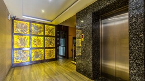 A modern elevator with a metallic finish, adjacent to a wall with a marble-like pattern. - Treebo Shivani (Indore)