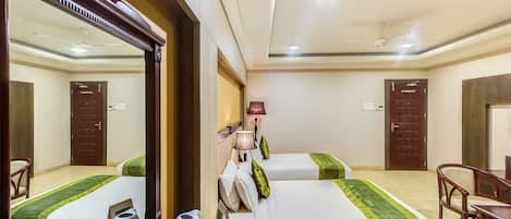 A hotel room with two beds, a desk, a chair, a mirror, and a ceiling fan.
