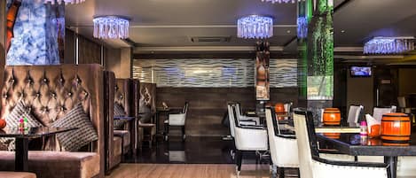 A modern lounge area with plush seating, ambient lighting, and a bar area.