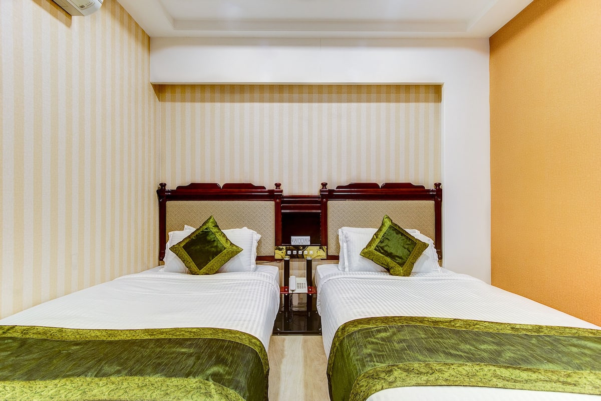 A hotel room with two single beds, a small table, and a telephone.