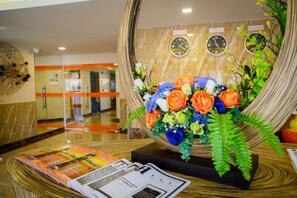 A reception area with a floral arrangement, clocks, and magazines on a table. - C-View Boutique (Pattaya)