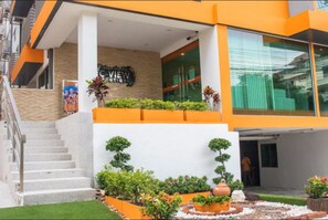 A modern hotel entrance with a staircase, a sign reading "C-View Boutique," and a well-maintained garden area. - C-View Boutique (Pattaya)