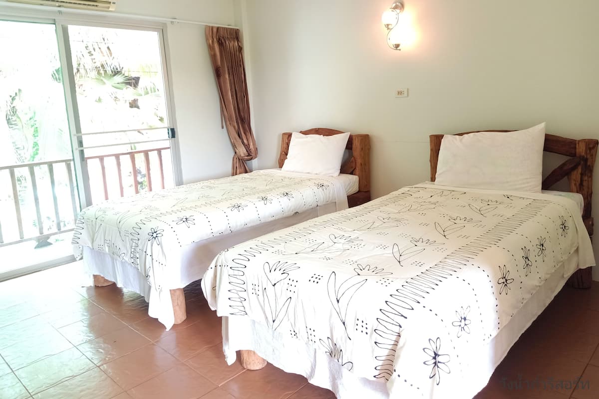 A room with two beds, a balcony, and a ceiling fan.