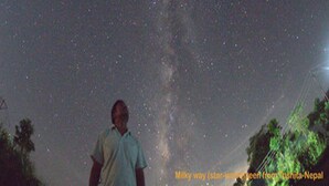 A person standing under a starry sky with the Milky Way visible.