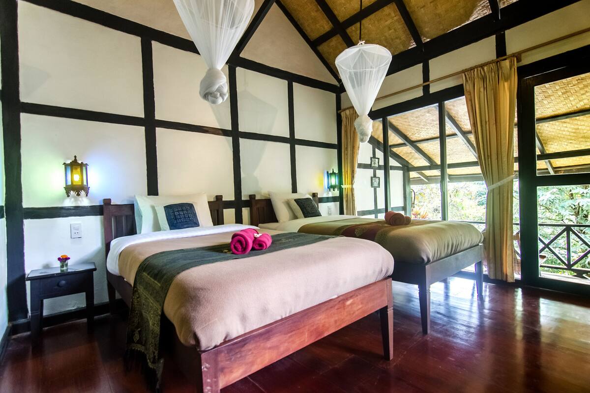 Une chambre dotée d’un grand lit, de tables de chevet et offrant une vue sur la verdure environnante.
