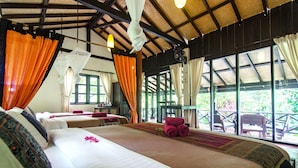 A room with two beds, a table, and chairs near large windows.