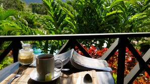 A table with a cup of tea, a glass jar, and a book titled "Poetry for Me" set against a backdrop of lush greenery and distant mountains.