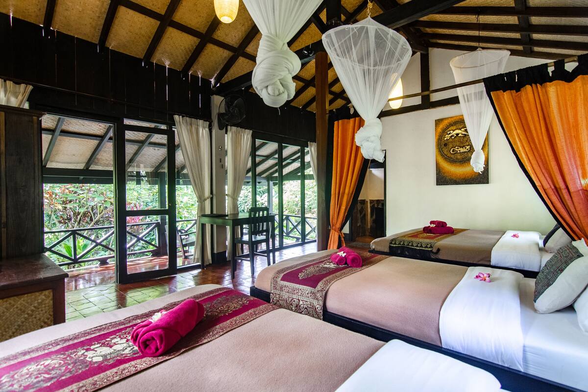 Une chambre d’hôtel avec deux lits, un plafond en bois et une vue sur la verdure environnante.