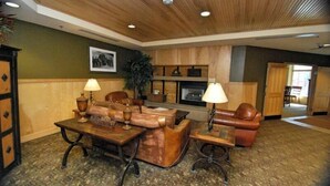 A lobby with a wooden ceiling, a fireplace, leather sofas, and a patterned carpet.
