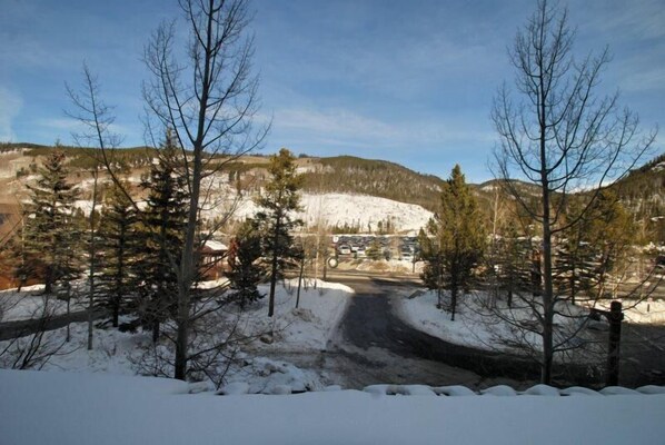 A snowy landscape with a road leading to a building, surrounded by trees and hills.