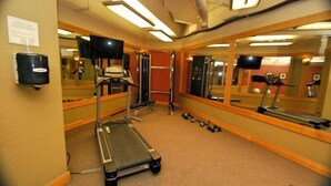 A gym with exercise equipment, mirrors, and a treadmill.