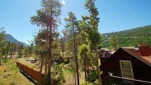 A cabin with a wooden exterior, surrounded by tall pine trees and a mountainous backdrop. - Snake River Village 2 Bedroom Apartment by Key to the Rockies (Keystone)