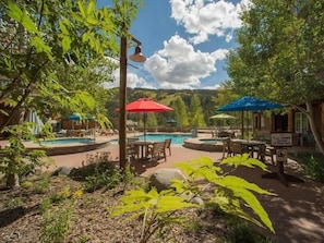 A pool area with multiple umbrellas, lounge chairs, and a sign indicating showering before entering the pool.