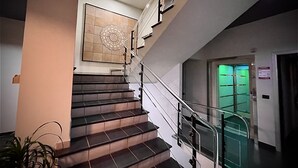 Una escalera moderna con barandillas de vidrio y un elemento decorativo en la pared.