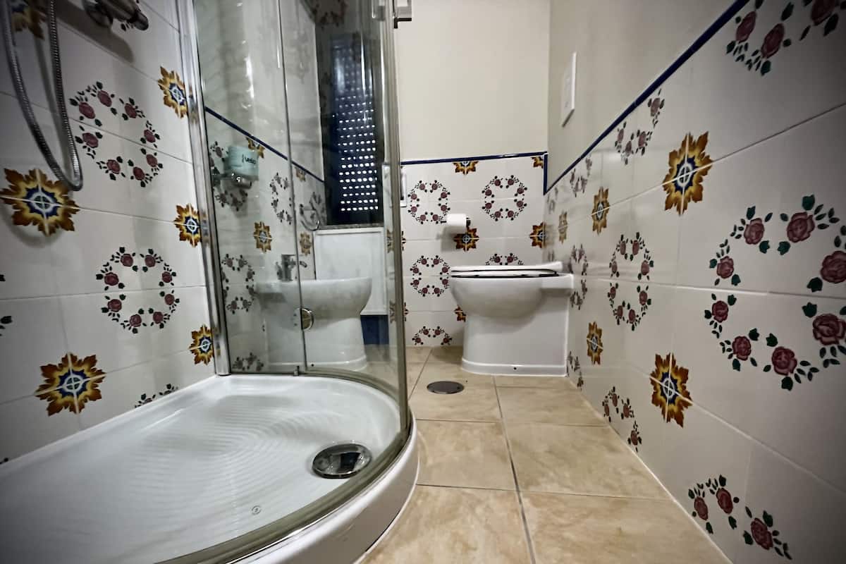 A bathroom with a glass-enclosed shower, a toilet, and a sink.