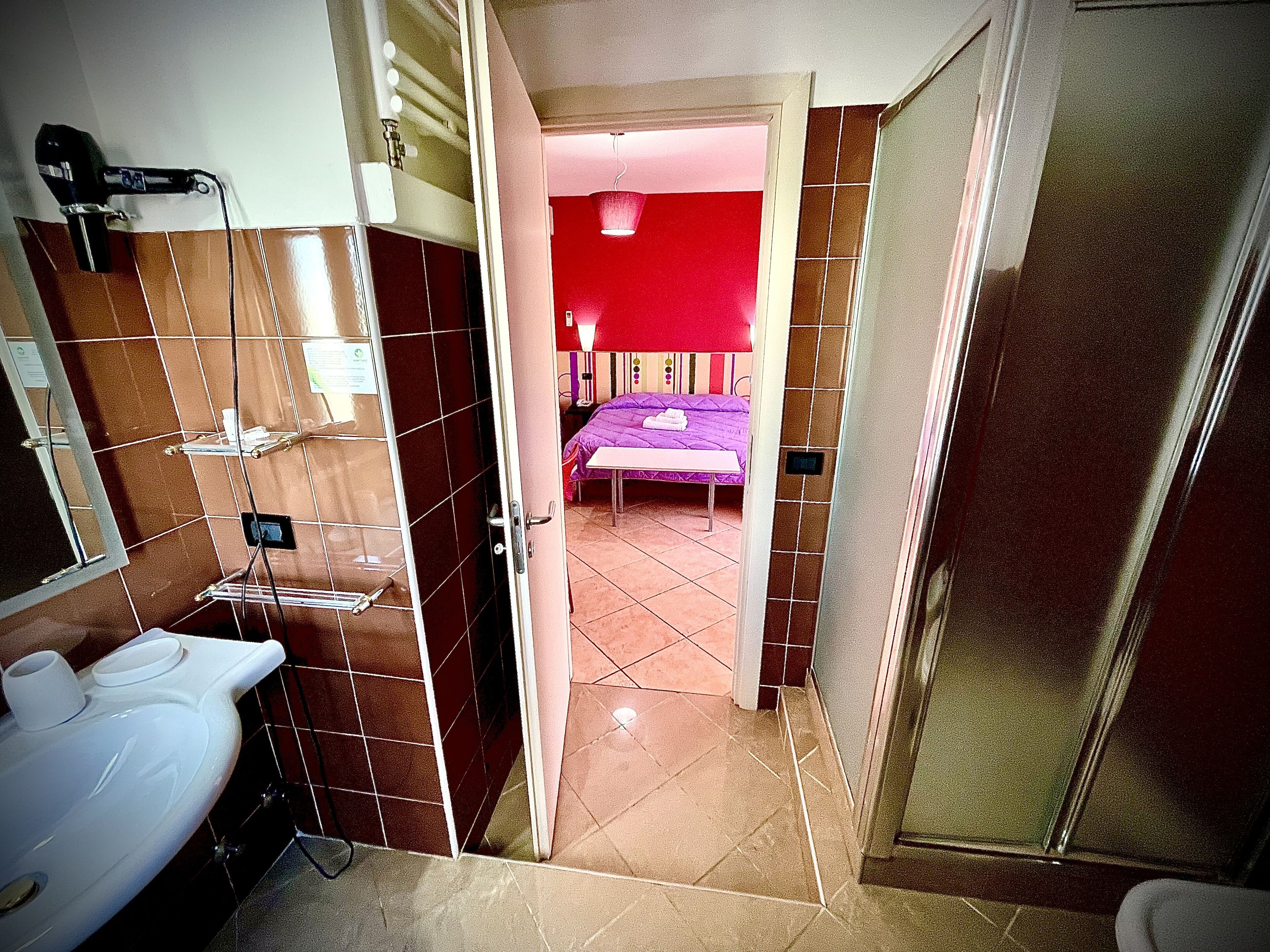 Un baño con un lavamanos blanco, un espejo y una zona de ducha.