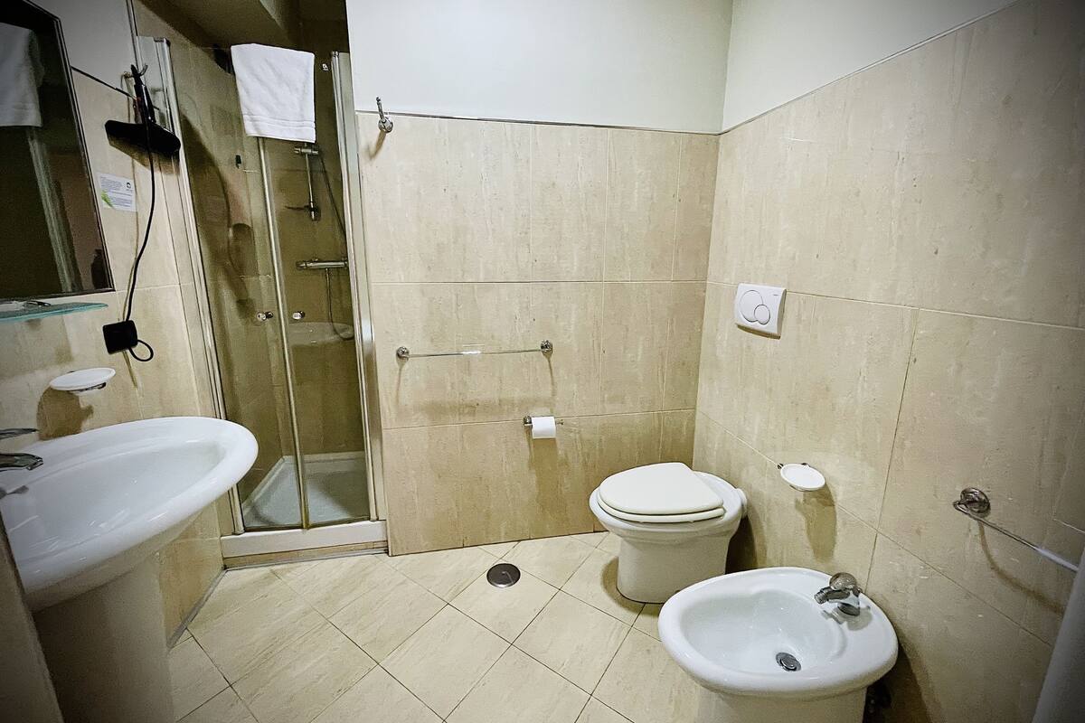 A bathroom with a sink, toilet, bidet, and glass shower enclosure.