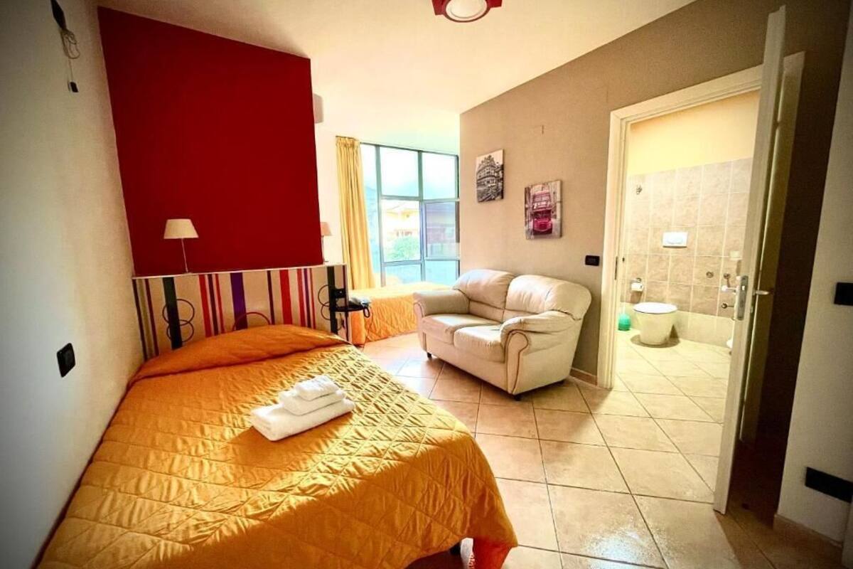 A hotel room with a bed, a chair, a window, and a bathroom.