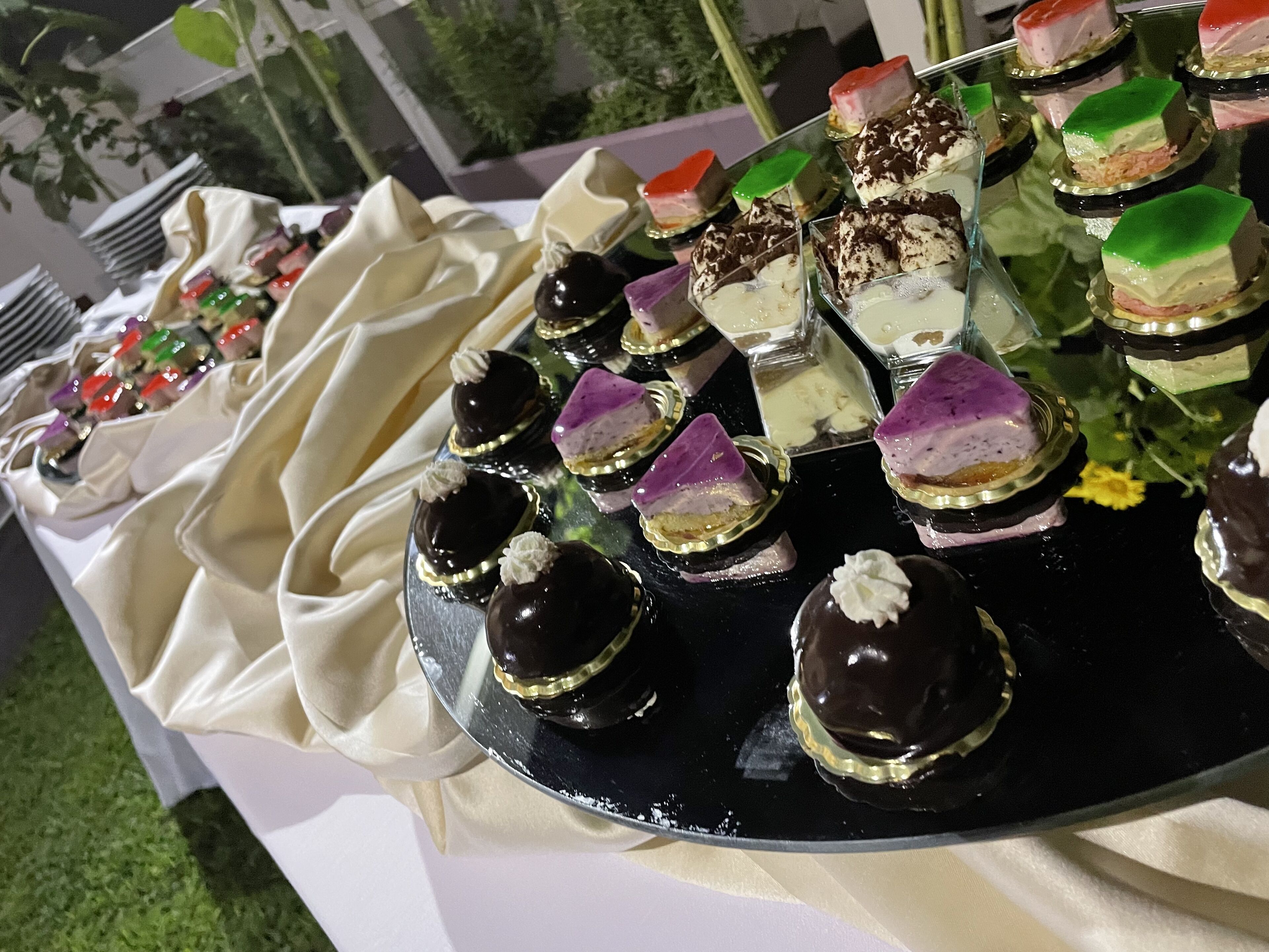 Une présentation de desserts comprenant divers gâteaux et pâtisseries disposés sur un plateau réfléchissant.