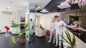Un moderno hall de hotel con mostrador de recepción, un espejo grande y una planta en maceta.