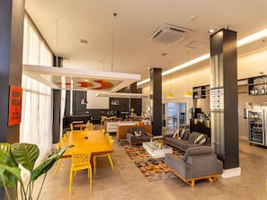 A modern interior with a dining area, sofas, a kitchen, and a bar area.