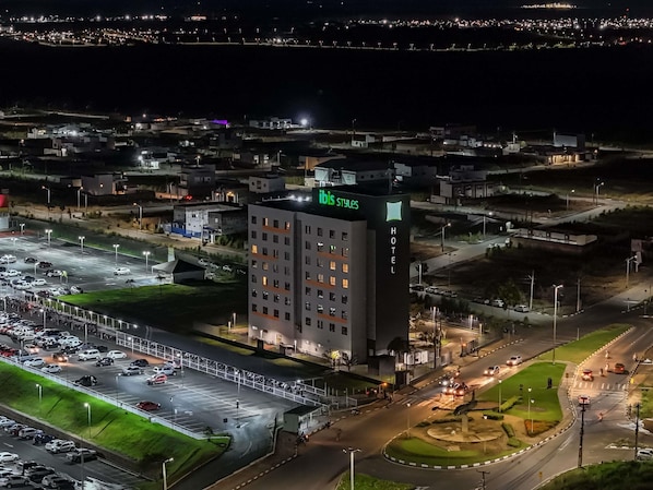 A multi-story hotel with a prominent 'ibis styles' sign, surrounded by a parking lot and a roundabout.