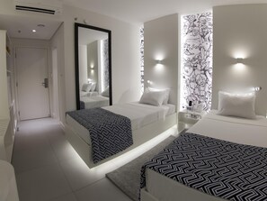 Ein modernes Hotelzimmer mit einem großen Bett, einem kleineren Bett, einem Spiegel und einer Wand mit einem Schwarz-Weiß-Muster.