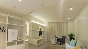 A modern living room with built-in shelves, a flat-screen TV, a laptop on a small table, a sofa with cushions, and a large window with curtains. - Ibis Styles Boa Vista (Boa Vista)