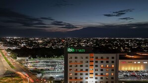 A hotel named ibis styles with a parking lot and a view of the city at night. - Ibis Styles Boa Vista (Boa Vista)