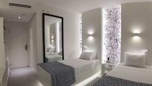 A modern hotel room with a large bed, a smaller bed, a mirror, and a wall with a black and white pattern. - Ibis Styles Boa Vista (Boa Vista)