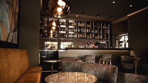 A bar area with seating, a marble table, and a wall of liquor bottles. - Hotel Rosengarten  (Zweibruecken)