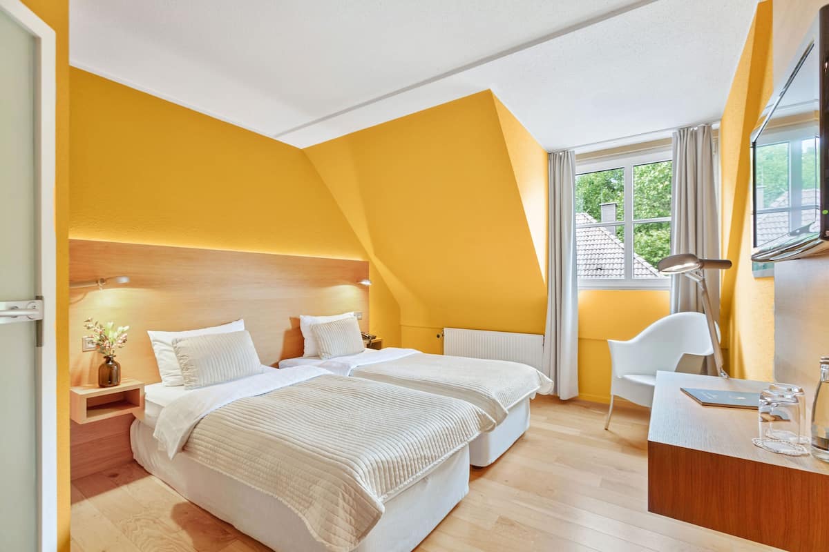 Ein Schlafzimmer mit zwei Betten, einem Schreibtisch und einem Fenster mit Vorhängen.