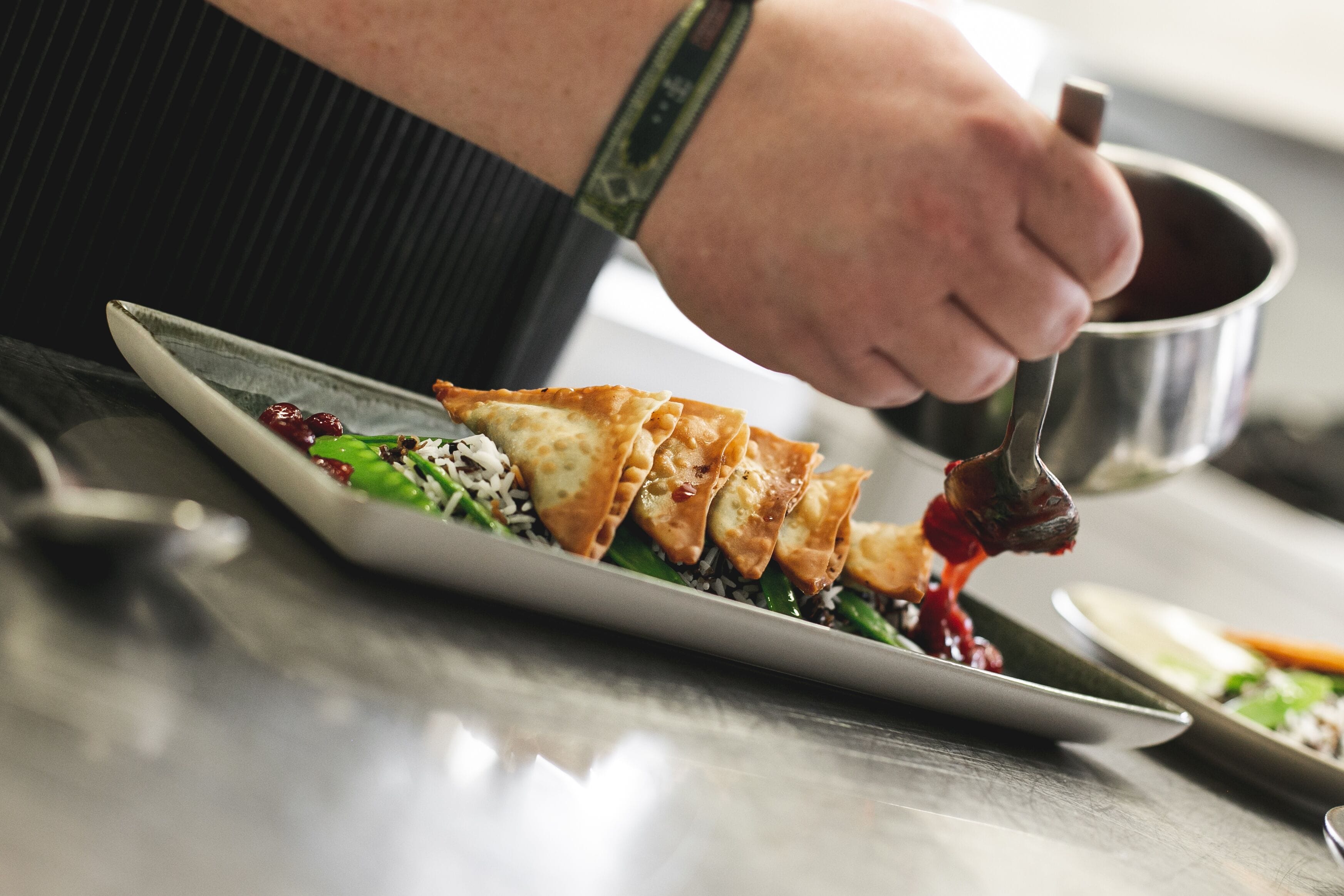 A person serving food from a pot onto a plate.