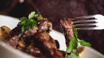 Ein Nahblick auf ein Gericht mit Fleisch und Gemüse, garniert mit Kräutern, auf einem weißen Teller.
