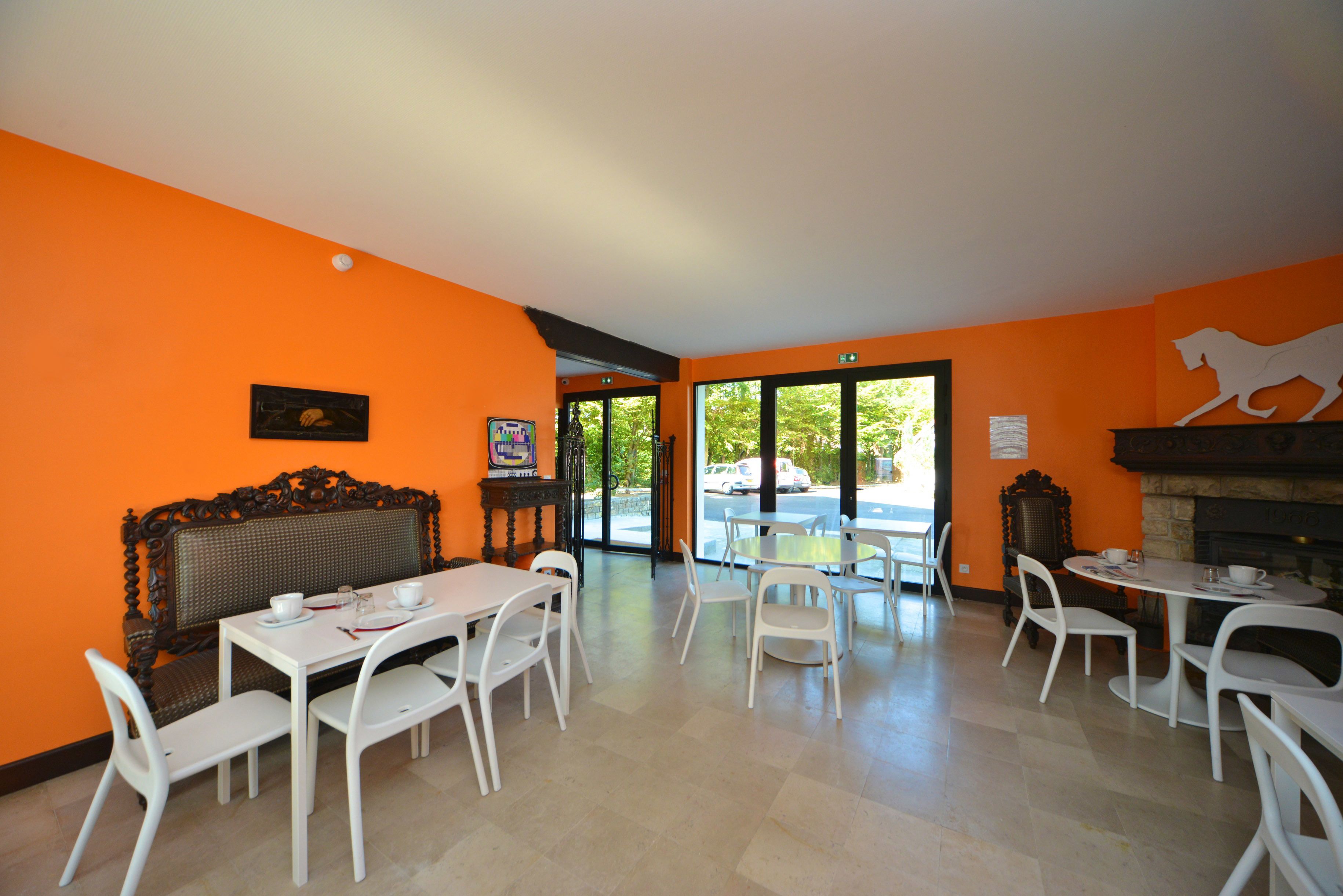 A dining area with white chairs and tables, a fireplace, and a view of the outdoors.
