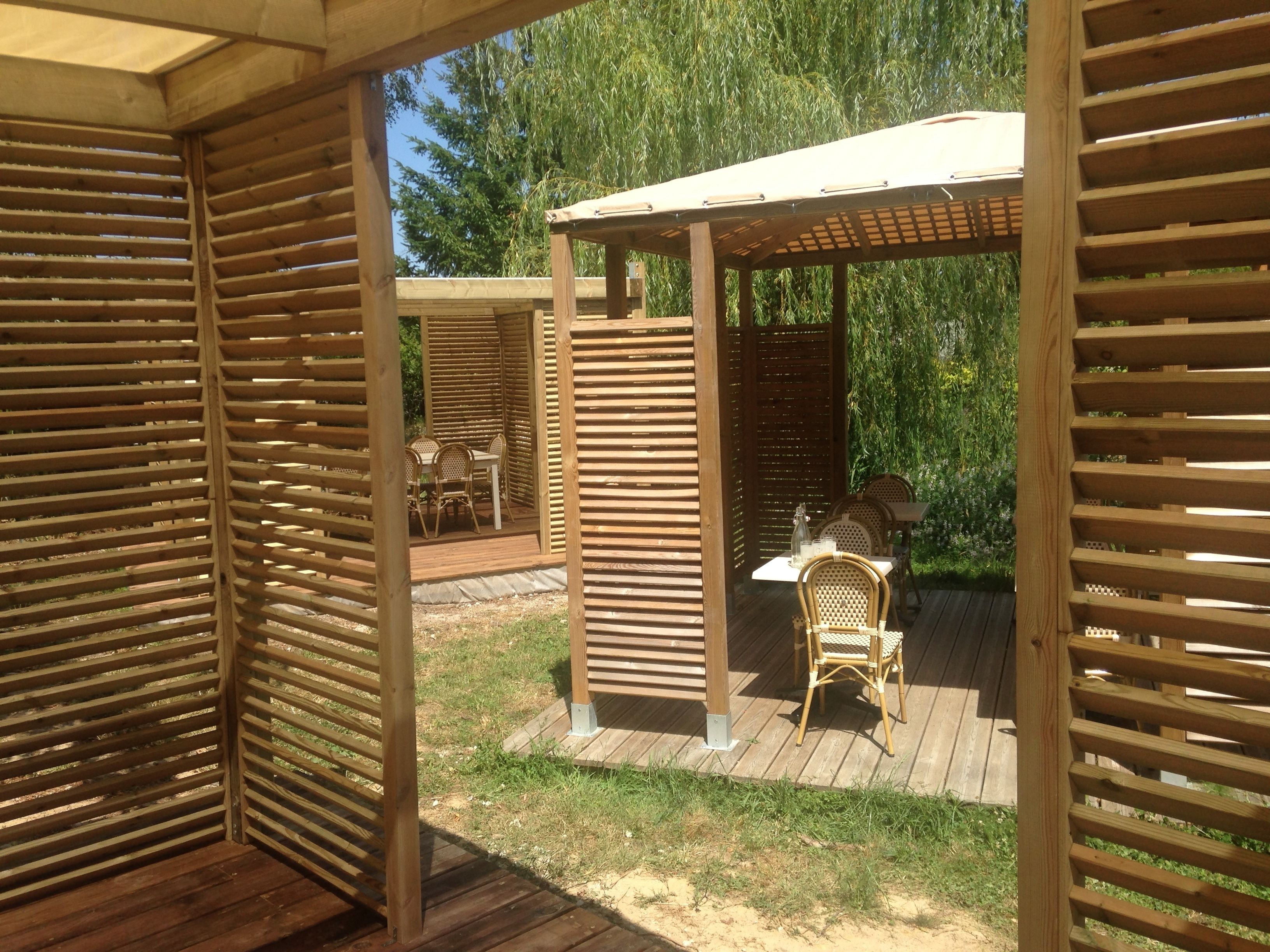 Una terrassa de fusta amb una pèrgola i zona d'estar a l'aire lliure.