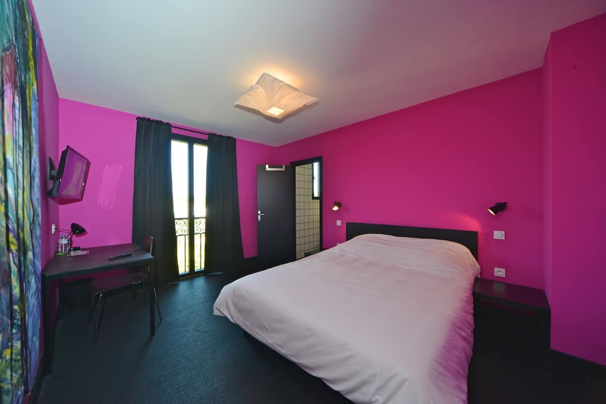 A room with a bed, desk, chair, and a window with curtains.