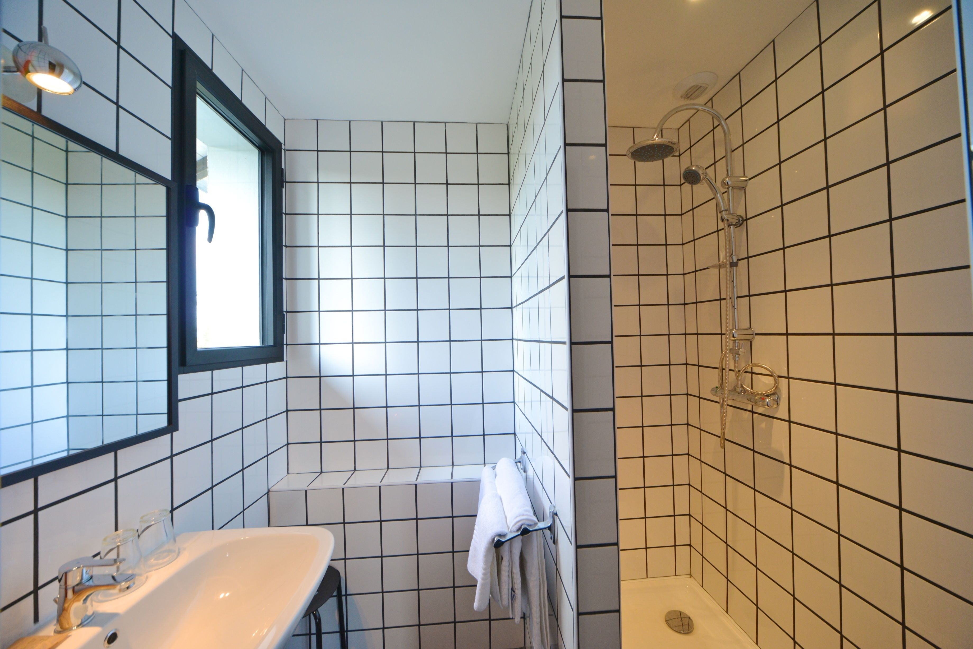 Een badkamer met een wit wastafel, spiegel en douche.
