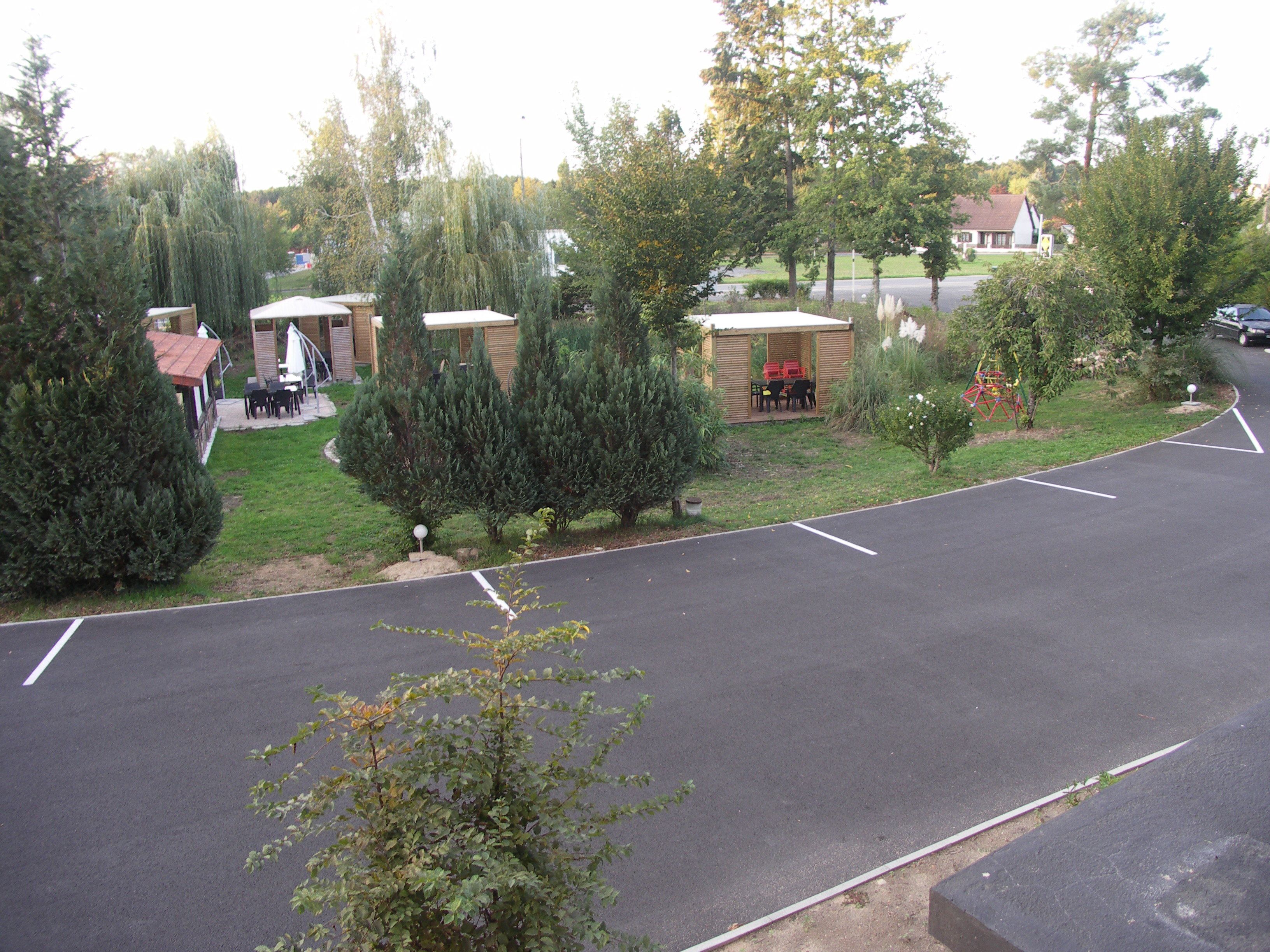 A parking lot with a few trees and a small building with outdoor seating.