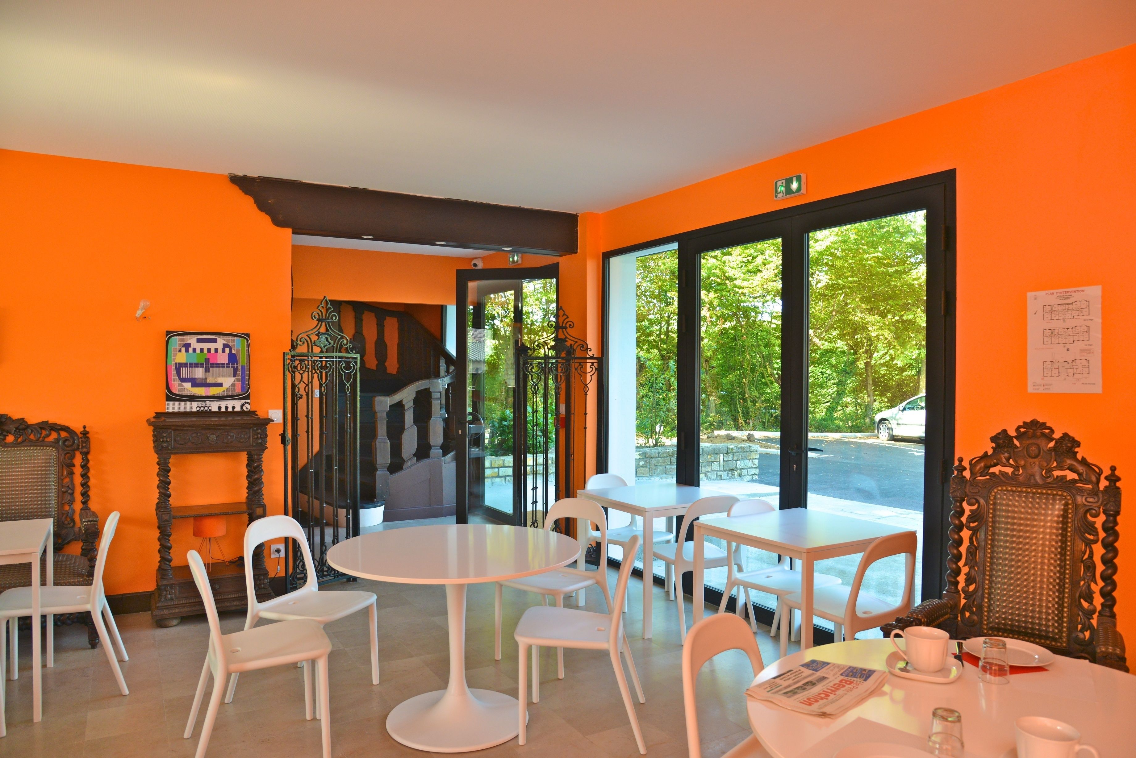 A bright orange room with white furniture, large windows, and a staircase leading to another level.