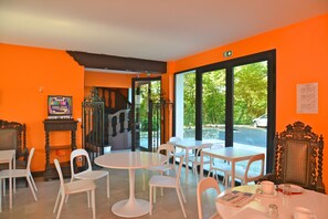 A bright orange room with white furniture, large windows, and a staircase leading to another level. - Logis Hôtel Restaurant La Mire (Mereau)