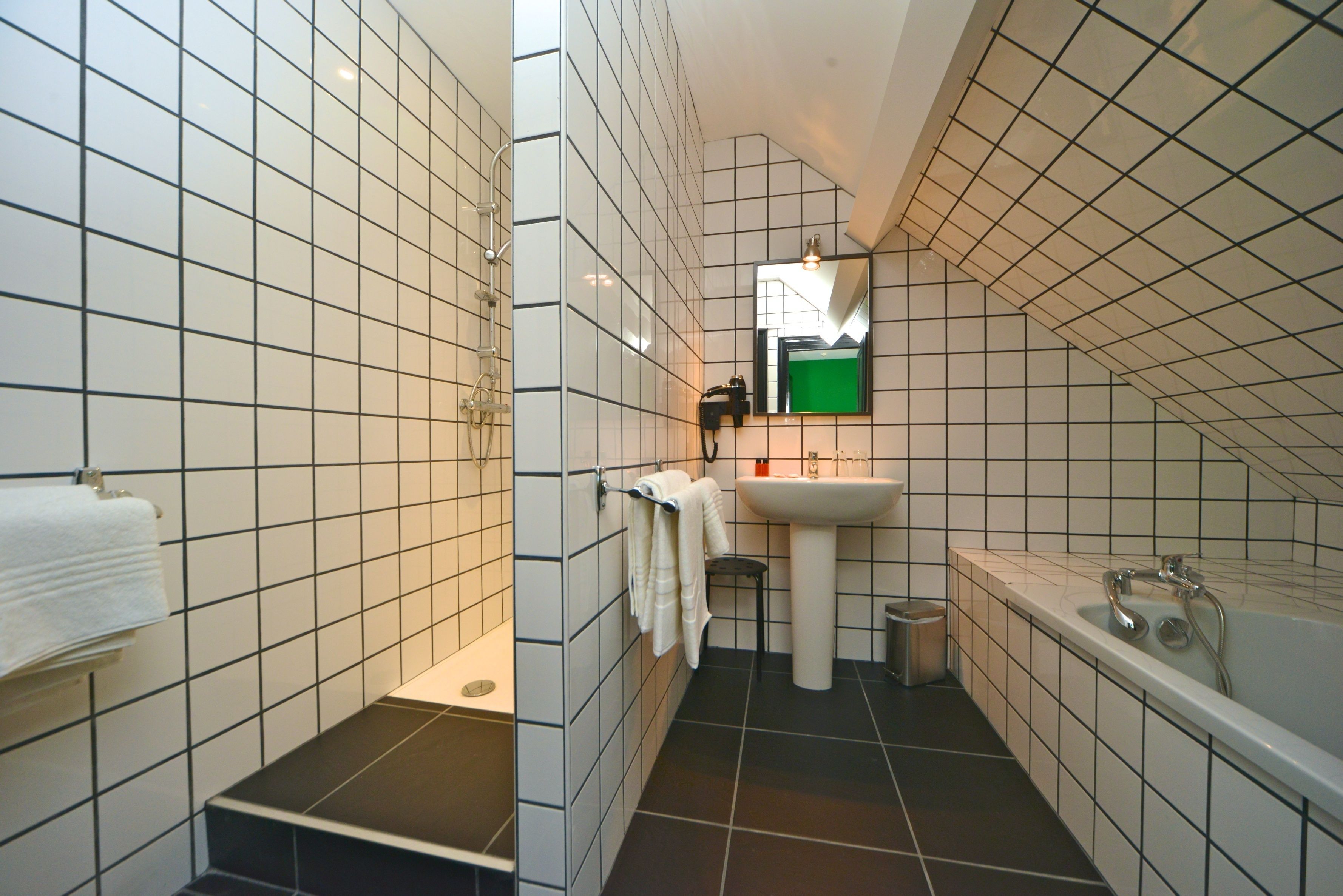 Un baño moderno con azulejos blancos y negros, un lavabo, un espejo y una bañera.
