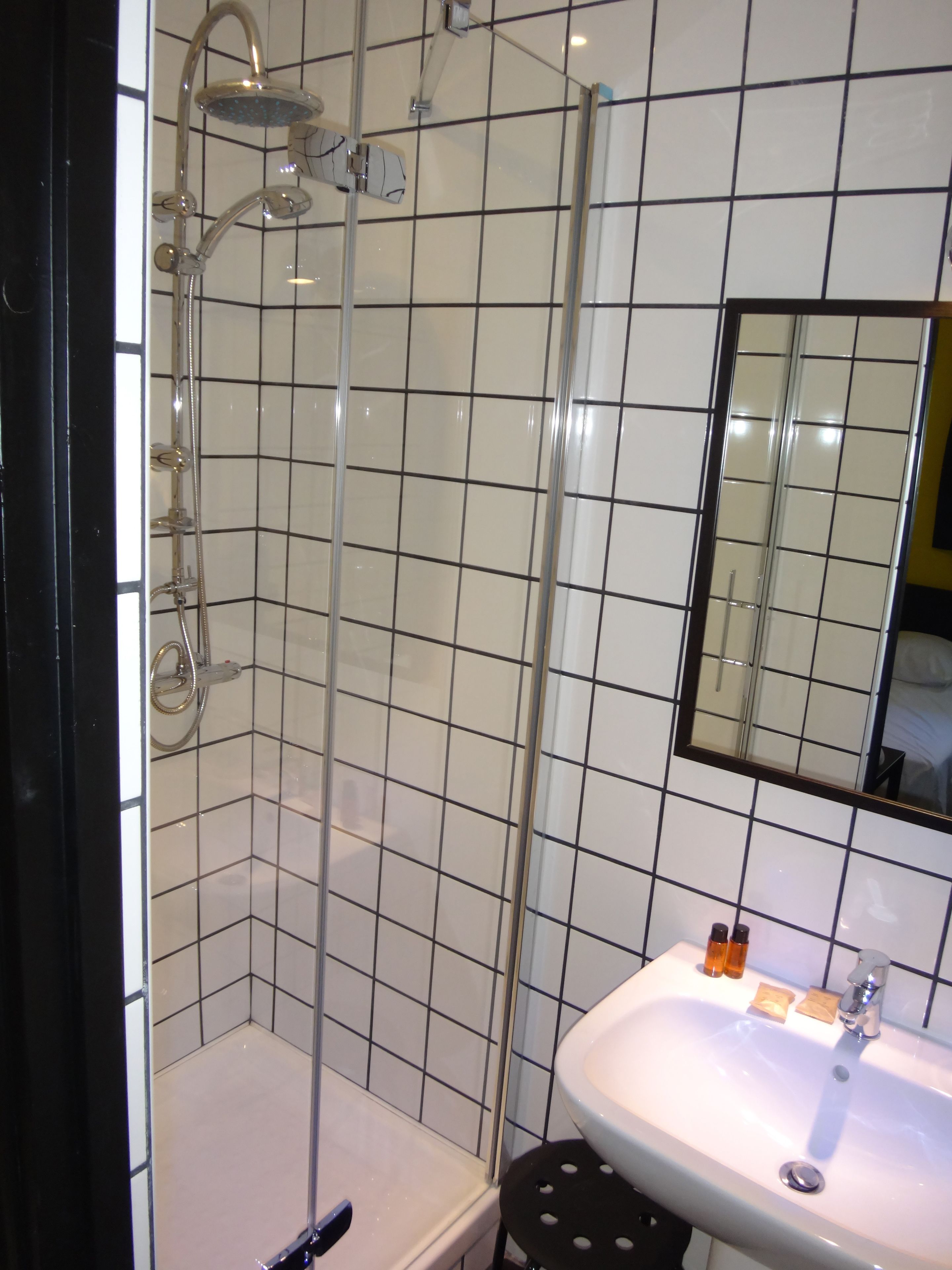 A bathroom with a glass-enclosed shower, a white sink, and a mirror above the sink.
