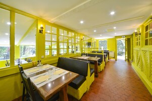 Un restaurante con paredes amarillas, mesas de madera y asientos tapizados en negro.