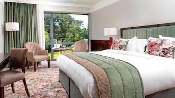 A hotel room with a large bed, two chairs, a desk, and a view of the outdoors.