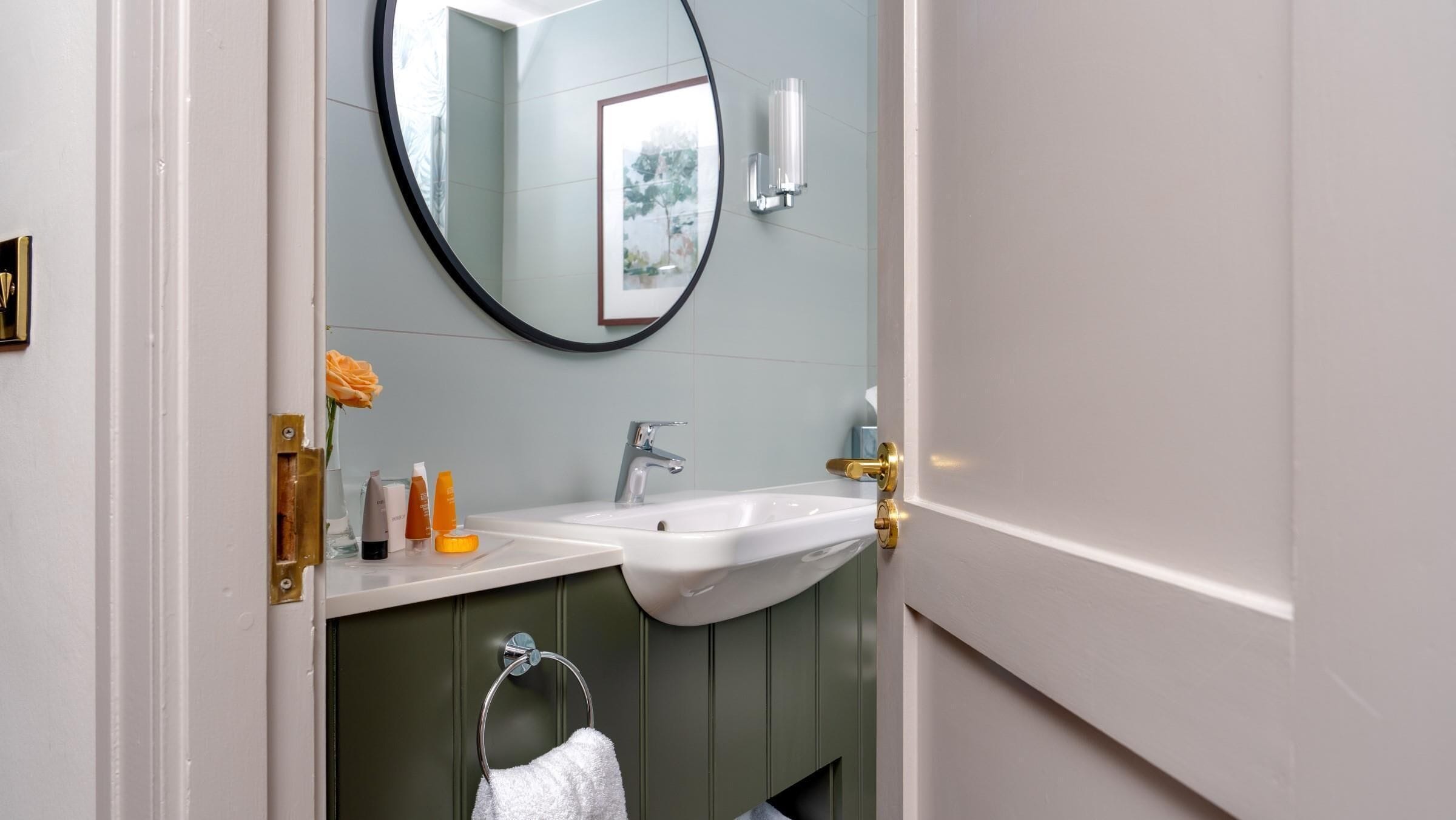 Une salle de bain avec un lavabo blanc, un miroir et un porte-serviette.