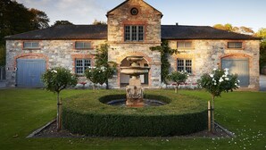 A stone building with a central fountain, surrounded by a well-manicured lawn and small trees.