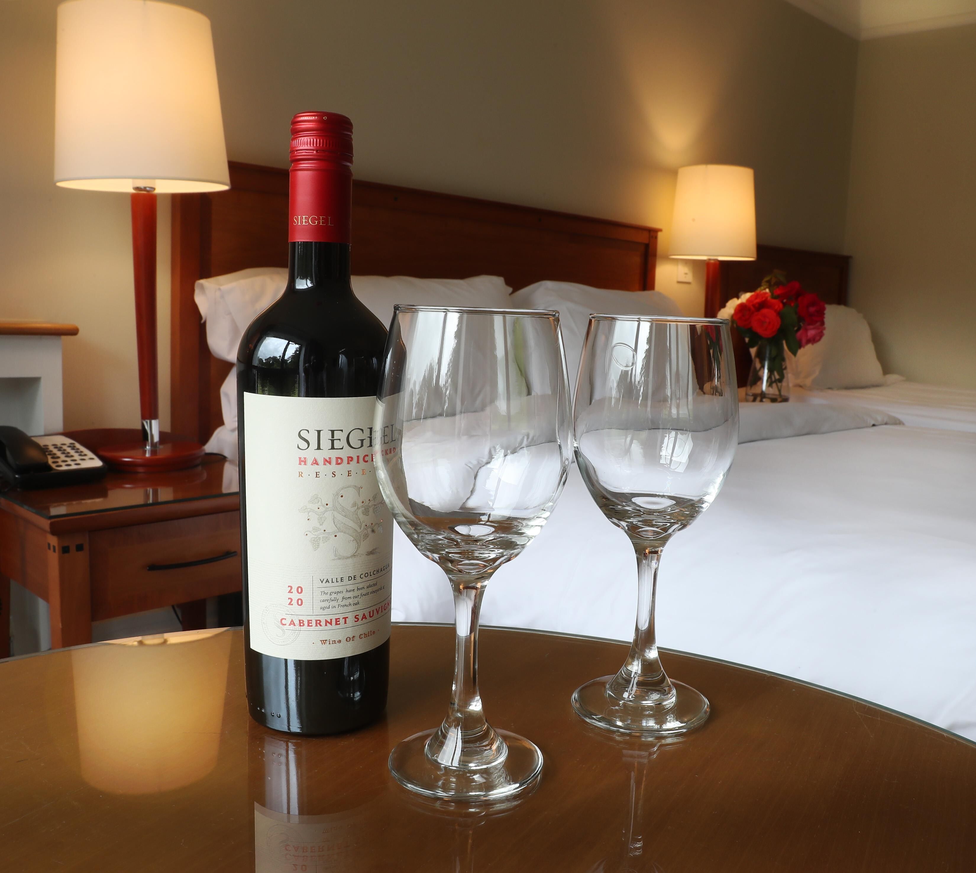 Una bottiglia di Cabernet Sauvignon Siegel, selezione 2020, e due bicchieri da vino su un tavolo d'hotel.